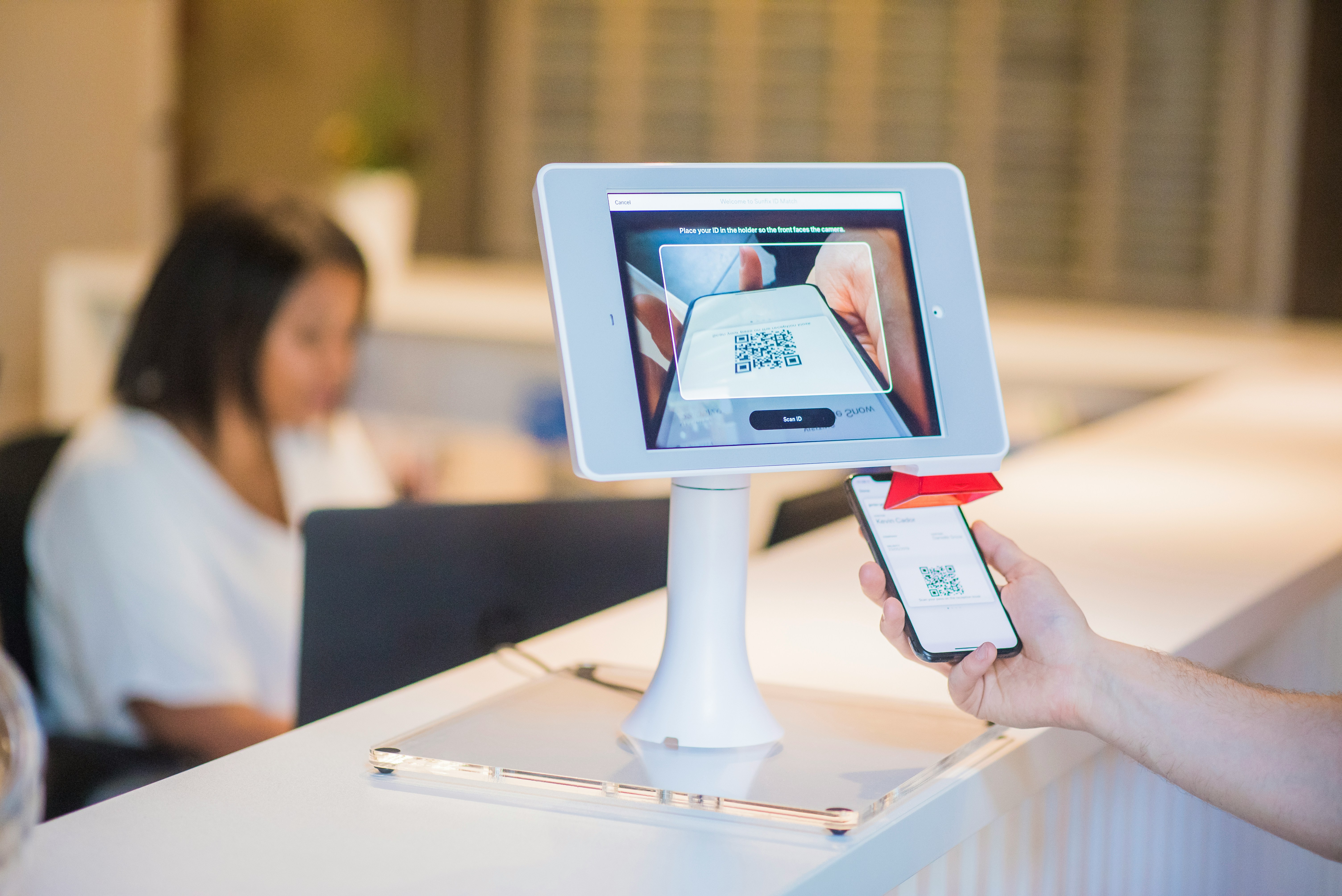Une vendeuse derrière un comptoir tenant un terminal de paiement
